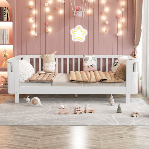 White children's bed with pink bedding in a room decorated with string lights and toys.